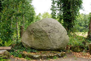 Der gro&szlig;e Gedenkstein f&uuml;r Hermann L&ouml;ns (1866&ndash;1914) steht  bei Wahrenholz in Niedersachsen.  Das Denkmal liegt idyllisch eingebettet in eine bewaldete Landschaft mit Farnen, Efeu und Laub.