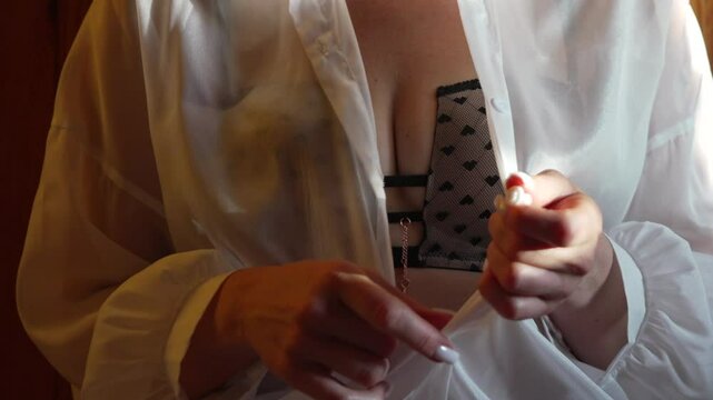 Woman unbuttoning shirt revealing black lace bra with hearts.