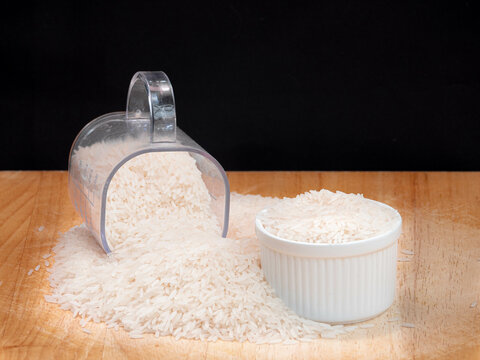 White Rice in Measuring Cup and Bowl on Wooden Surface