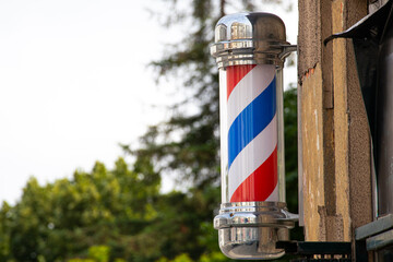 Classic Barber Pole Sign Outside Barbershop. Traditional red, white, and blue barber pole spinning...
