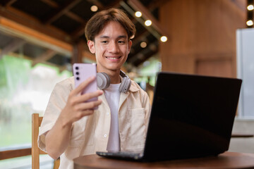 Handsome young non binary man sitting in cafe restaurant using laptop computer