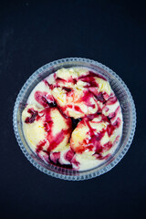 Ice Cream with Red Topping. Delicious vanilla ice cream topped with vibrant red berry sauce, perfect for dessert menus and food advertising