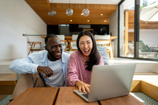 Happy multiethnic diverse couple, people using digital laptop for online shopping or payment.