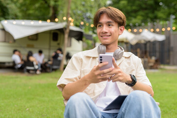 Young non binary person having road trip and camping with friends in nature using phone