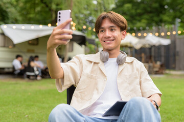 Young non binary person having road trip and camping with friends in nature using phone