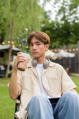 Young non binary person having road trip and camping with friends drinking chocolate drink