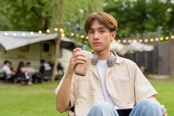 Young non binary person having road trip and camping with friends drinking chocolate drink