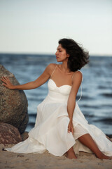 Ocean Breeze Elegance: Woman in White Dress on Coastal Rocks
A woman in a flowing white dress...