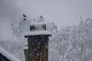 Russian winter in northern olden time hamlet. Snowfall. Smoke is coming from chimney. Frozen...