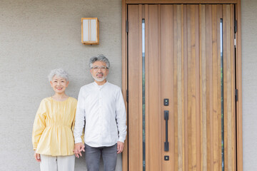 笑顔で住宅の前に立つシニアカップル