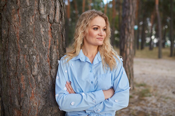 Confident Woman with Arms Crossed by Tree