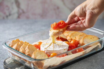 Baked soft cheese Brie or Camembert with tomato, garlic and herbs