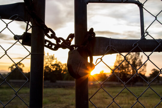 Morning sun shining through silhouetted padlock and gates