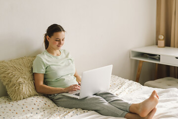 Young beautiful woman working on laptop on bed. Concepts of technology and freelance work.