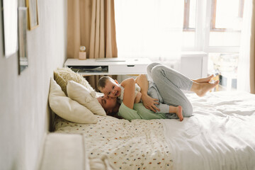 Home portrait of a baby boy with mother on the bed relaxing and playing in the bed at the weekend...