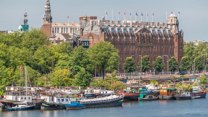 Obraz premium Amsterdam skyline with boats at the pier in Oosterdok harbor with Scheepvaarthuis aerial timelapse. Amsterdam, The Netherlands