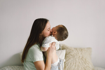 Home portrait of a baby boy with mother on the bed relaxing and playing in the bed at the weekend...