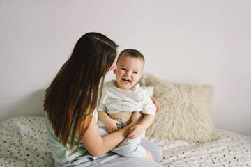 Home portrait of a baby boy with mother on the bed relaxing and playing in the bed at the weekend...