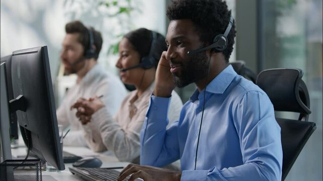 Multinational team African male callcenter operators thumbs up headset smiling office computer support female Indian coworker typing customer service happy Caucasian colleague job call center business - Powered by Adobe