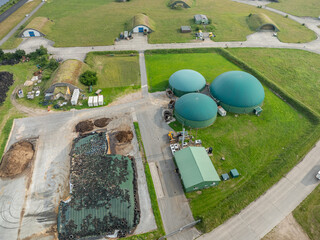 Aerial view of a modern biogas plant with green fermentation tanks, combined heat and power...
