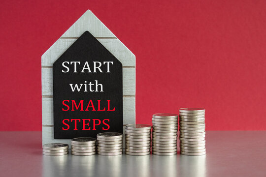 Start with small steps symbol. Concept words Start with small steps written on a black board. Silver coins arranged in a graph in front. Beautiful red background, grey table. Business concept.
