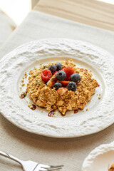 Crumble dessert with berries on white ceramic plate