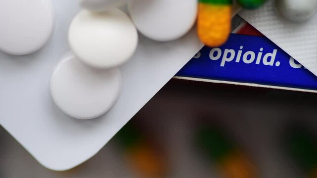Macro close up of medicine tablets and capsules on a box of medicine containing opioid. A drug addiction concept.