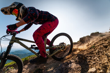 Cyclist riding bike on rock with beautiful mountains in background. Extreme sport and enduro bike...