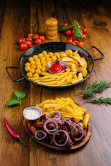 Delicious array of snacks with fries, sauces, and fresh tomatoes on wooden table