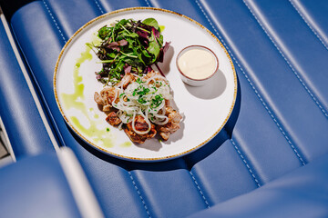 Delicious grilled chicken with fresh salad and dipping sauce on blue seating