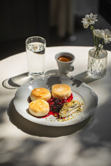 Portion of curd pancakes syrniki with berry jam and sour cream