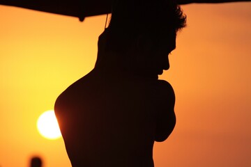 Silhouette of man against orange sky at beach