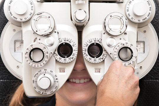 optometrist using a phoropter to measure a girl's eyesight