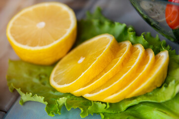 Top view of lemon sliced into rings lying on green salad leaves. Close-up of salad ingredient
