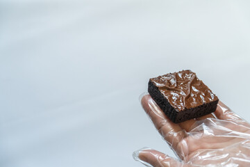 Hand in Clear Glove Presenting Unpackaged Brownie, Bright Background