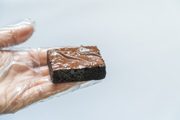 Hand in Clear Glove Elevating Fuggy Brownie, White Background