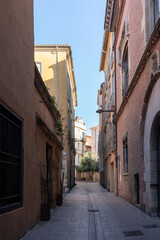 Fototapeta premium Peaceful narrow alley with historic buildings in Perpignan, France
