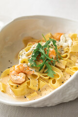 Fettuccine pasta with shrimp and creamy sauce garnished with arugula