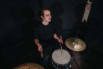 A young drummer playing the drums during a music rehearsal in a studio setting. The scene captures musical expression, passion, and the atmosphere of preparation for an upcoming performance or concert