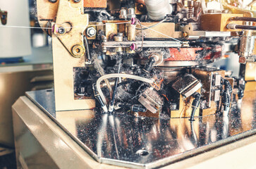 Knitting machine with yarn dust. Close-up of knitting machine with cotton yarn in a sock factory.