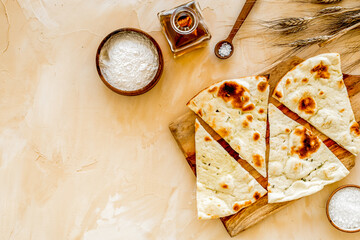 Focaccia ingredients. Wheat ears, flour, oil near bread on beige background top-down copy space