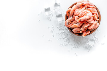 Shrimps in bowl near ice on white background top view copy space