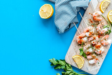Shrimp skewers - appetizer in mediterranean kitchen - on blue table top view copy space