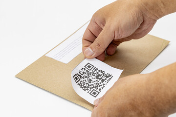 Person is attaching dummy QR code label to brown envelope, demonstrating modern and efficient way...
