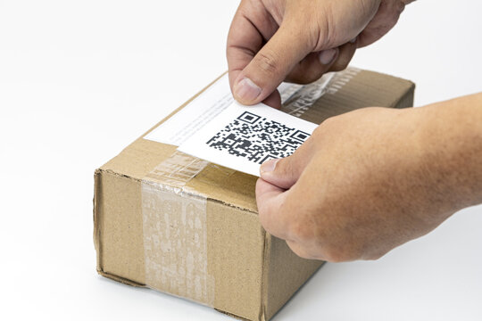 Hands placing dummy QR code label on cardboard shipping box, symbolizing modern logistics and efficient package tracking. scene highlights integration of technology in shipping processes