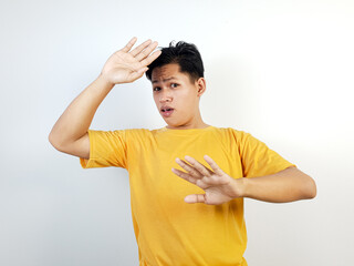 Young Asian Man Wearing Yellow Shirt Making Surprised Gestures Against A White Background
