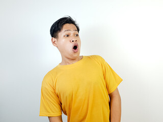 Surprised Asian Man Wearing a Yellow Shirt Against a Bright Background