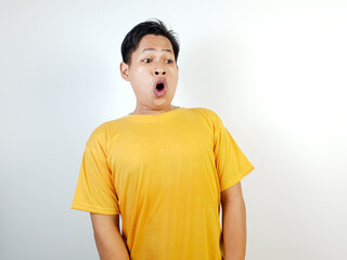 Surprised Asian Man Wearing a Yellow Shirt Against a Bright Background