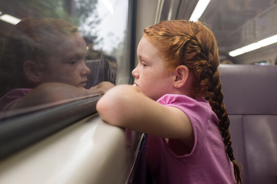 Young girl looking out the window of a train