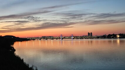 Obraz premium 양화대교를 중심으로 서울 한강에 비친 붉은 노을과 도시의 불빛